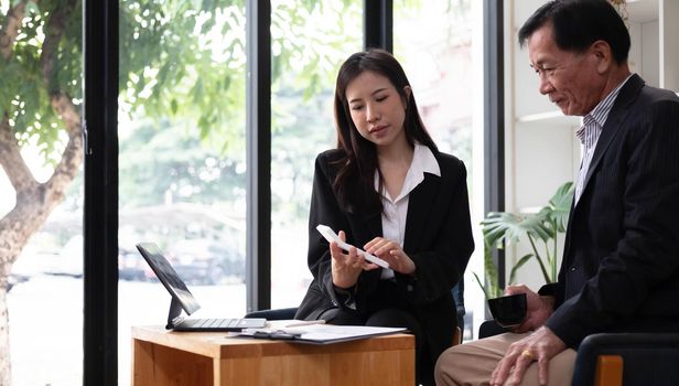 Middle aged businessman having an informal meeting with his financial manager. asian businesspeople concept..