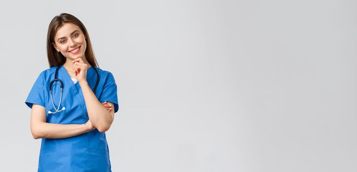 Medical workers, healthcare, covid-19 and vaccination concept. Upbeat smiling pretty nurse, doctor in blue scrubs, working clinic, looking with enthusiastic gaze camera, listening to coworker.