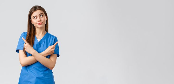 Healthcare workers, prevent virus, insurance and medicine concept. Nurse facing complicated choice. Doctor in blue scrubs, pointing sideways making tough decision, standing indecisive.