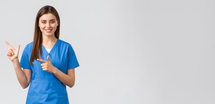 Healthcare workers, prevent virus, insurance and medicine concept. Professional smiling, attractive female nurse or doctor in blue scrubs, physician pointing finger left at banner, recommend clinic.