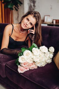 a beautiful woman lies with flowers roses and smiles.