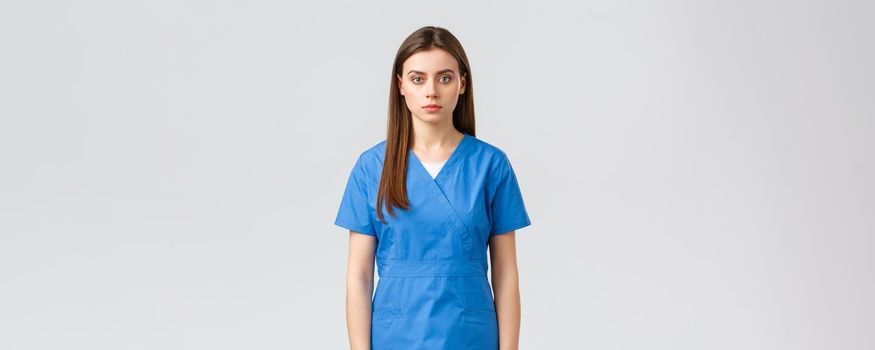 Healthcare workers, prevent virus, insurance and medicine concept. Serious-looking young medical worker, nurse or doctor in blue scrubs, looking determined and confident camera.