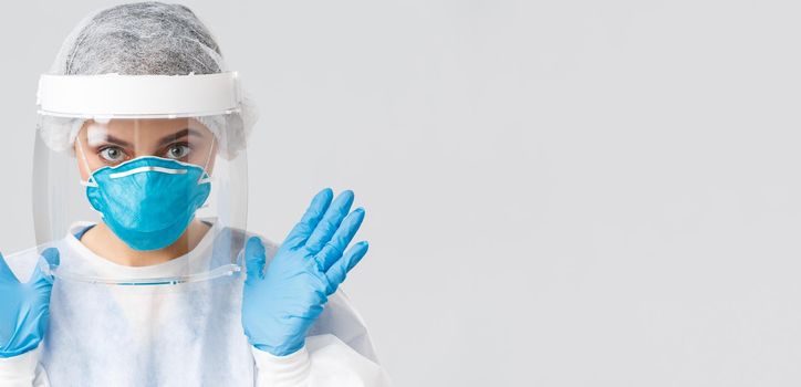 Covid-19, preventing virus, health, healthcare workers and quarantine concept. Close-up female doctor or nurse in personal protective equipment, rubber gloves and respirator showing hands.