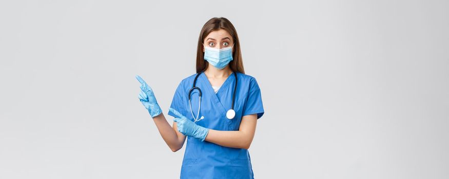 Covid-19, preventing virus, health, healthcare workers and quarantine concept. Interested and questioned female doctor, nurse in blue scrubs and medical mask, asking question pointing left.