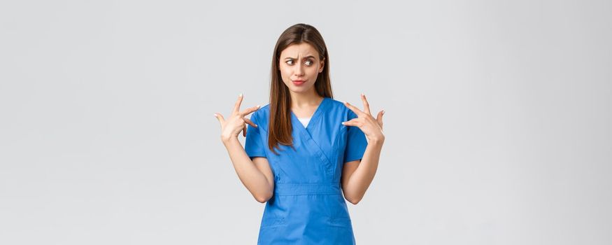 Healthcare workers, prevent virus, insurance and medicine concept. Concerned and bothered young female intern or nurse feeling reluctant and disgusted touching something nasty, grimacing.