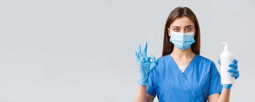 Covid-19, preventing virus, health, healthcare workers and quarantine concept. Confident serious female nurse, pretty doctor in scrubs and medical mask, show hand sanitizer, soap and okay sign.