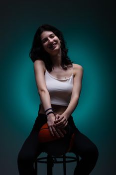 Teenage girl with dental braces holding basketball. Studio portrait on neon blue colored background.