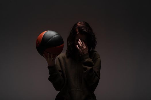 Teenage girl with basketball. Silhouette studio portrait on dark background.