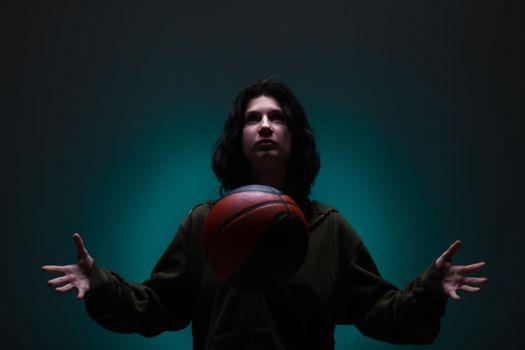 Teenage girl with basketball. Studio portrait with neon blue colored background.