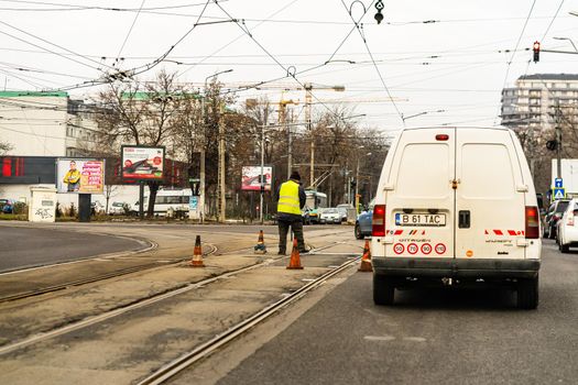 Worker arranging traffic cone on tram railway in Bucharest, Romania, 2021