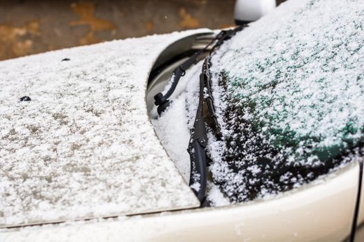 Snow on car, windshield wipers with snow close up.