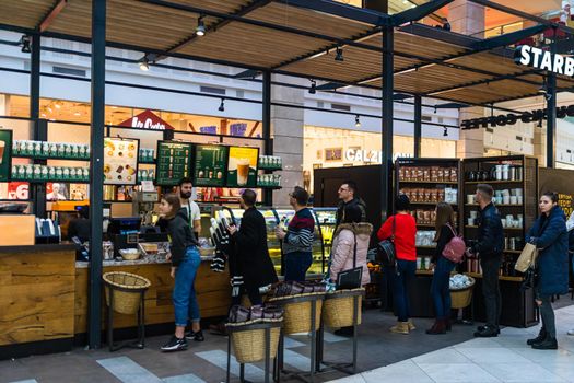 People sitting, waiting in line and working at the Starbucks at AFI Cotroceni Mall from Bucharest, Romania, 2020