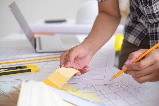 Young man was designing a building or architecture with a ruler, pen, pencil, tape measure, architect hat and other equipment.