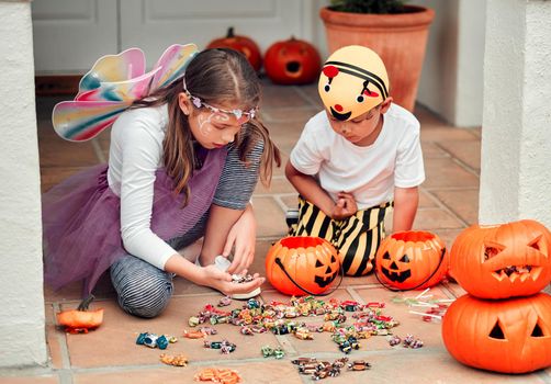 Shot of two adorable young siblings looking at their Halloween candy at home.