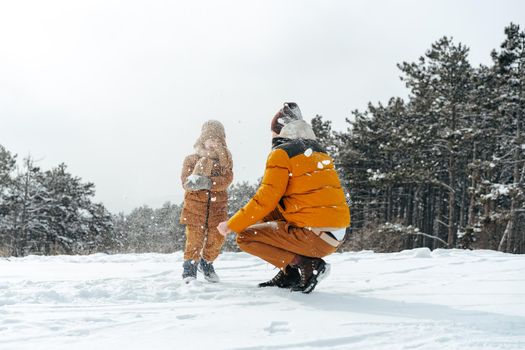 Father and son playing in the park on winter snowy day