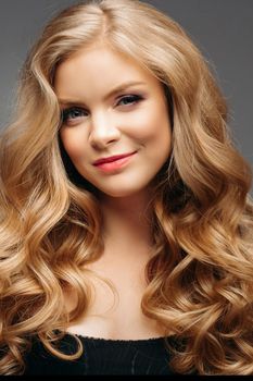 Studio fashion portrait of attractive sensual young woman with long wavy fair hair and blue eyes looking at camera. Natural beauty concept. Caucasian.