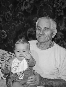 Rostov region, Russia, 2012-11-18, A very elderly man is in his room. grandpa is holding his little great-grandson in his arms.  Portrait of an old grandfather. Village life.