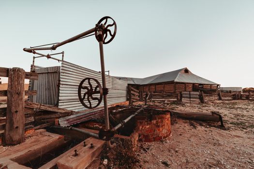 Old timber and corrugated iron shearing shed, rusting machinery and broken fencing in outback Australia