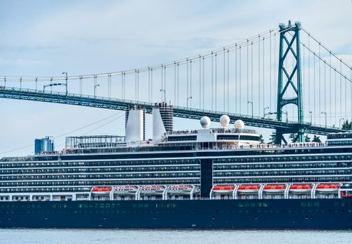 Close up view on huge ocean cruise ship passing famous Lion Gates Bridge in Vancouver, Canada