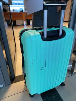 Broken blue suitcase at the airport. Incident with luggage during the flight