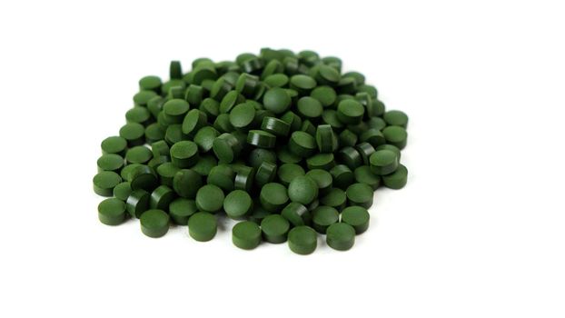 Spirulina algae tablets isolated on white background. Nutritional supplements, vitamins and health concept.
