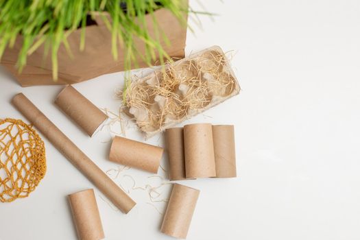 Household waste rollers from cardboard and paper lie on a white table, a knitted bag. The concept of recycling and environmental protection. Top view