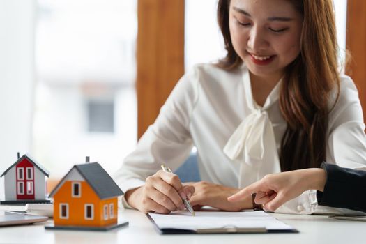 Close up of Business woman pointing and signing agreement for buying house. Bank manager concept