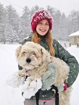 Portrait of A Smiling young girl holding up her Extremely Shaggy Dog Whose Paws are Caked in Snow. High quality photo