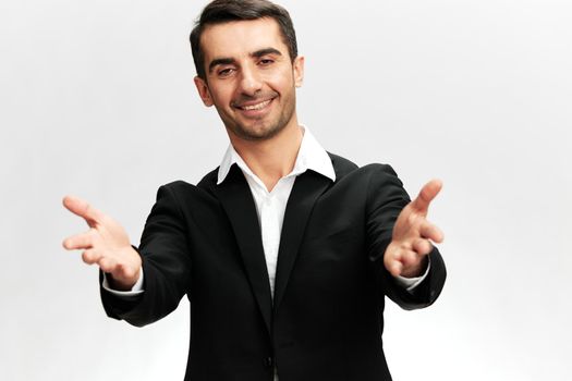 friendly greeting of a man in a black business suit stretches his hands forward with a smile light isolated background Copy space. High quality photo