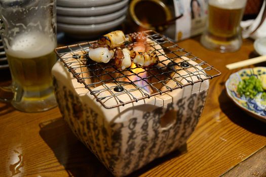 Selective focus of grilled octopus on charcoal stove. Food and travel concept.