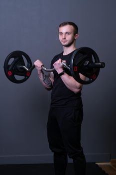 Guy with a barbell in a black fitness T-shirt muscular bodybuilder barbell fit, from strength active for workout and physical athletic, diet portrait. Lifting torso work, practicing arm