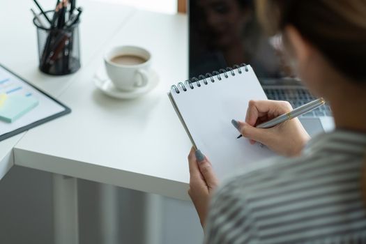 Business asian hand holding pencil and writing note on wood table,Checklist Notice Remember Planning Concept.