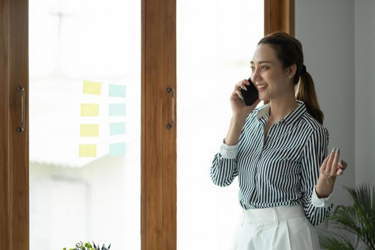 Portrait Female Entrepreneur. Cheerful asian Businesswoman Talking On Phone In Modern Office