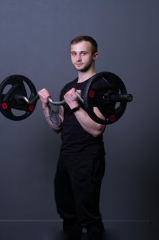 Guy with a barbell in a black fitness T-shirt muscular bodybuilder barbell bodybuilding, for strong training in gym for handsome body, background deadlift. Man young bar, health arm