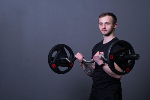 Guy with a barbell in a black fitness T-shirt muscular bodybuilder barbell bodybuilding, from strong active from guy from trainer body, diet triceps. Sportsman young work, practicing arm