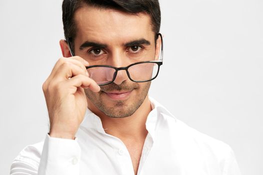 smart businessman with glasses in white shirts puts on glasses copy-space light background. High quality photo