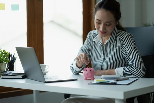 Asian woman hand putting money coin into piggy for saving money wealth and financial concept