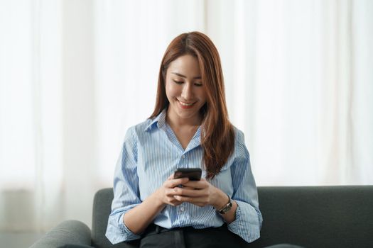 Happy asian girl holding cell phone using smartphone device at home. Smiling young latin woman blogger subscribing new social media, buying in internet, ordering products online in apps. hand close up.