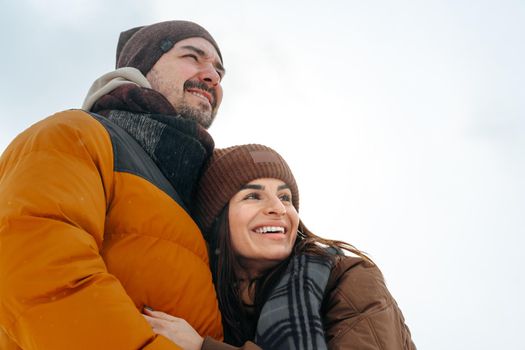 Young couple in love outdoor in snowy winter forest having a walk