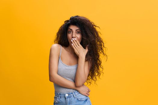 Surprised confused young arab lady covers her mouth with hand, holding hand on waist, isolated on orange background, collage. Shocking offer, news, great sale, advertising and app