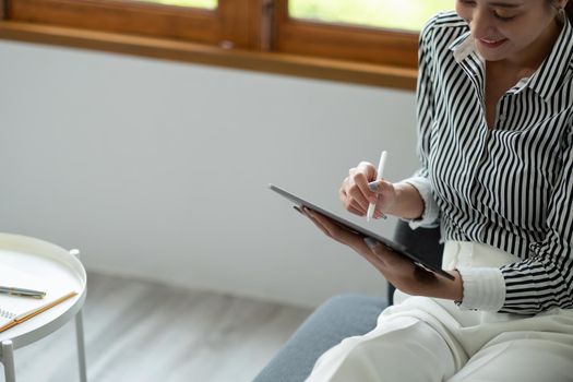 Close up hand of woman manager holding tablet and pen stylus in modern office.