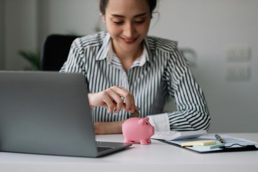 Asian woman hand putting money coin into piggy for saving money wealth and financial concept