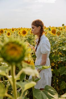 Woman in white dress with pigtails in a field of sunflowers summer landscape. High quality photo