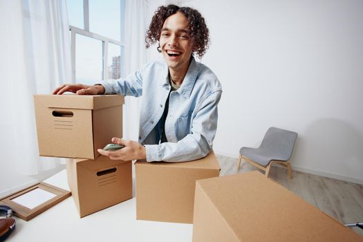 guy with curly hair with a phone in hand with boxes moving sorting things out. High quality photo