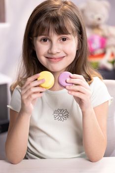 School girl wants to eat two macarons at the same time. Dessert, delicious. Tasty sweet color macaron. Feeling good, delicious.