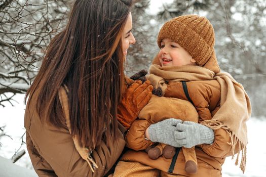 Woman with a little son on a winter hike in the snowy forest together