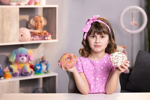 Lovely joyful school girl can not choose between a pink donut and yellow fresh macaroon. Healthy lifestyle, sweets, sweet tooth. Being on a diet.