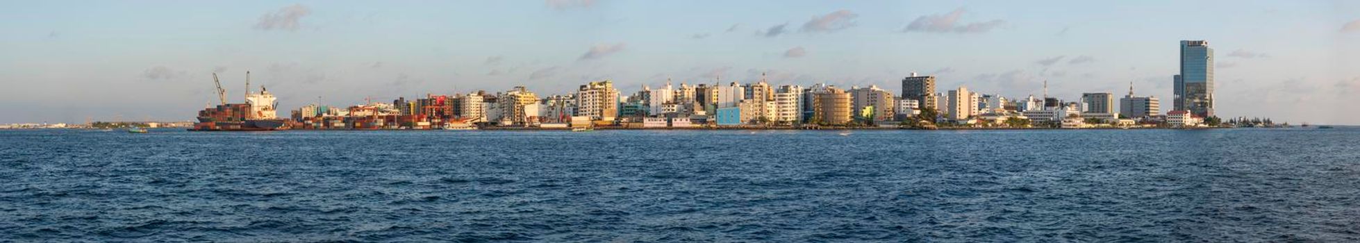 Panoramic scenic view of large island city of Male in Maldives with commercial shipping port and cargo ship