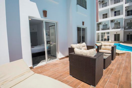 Outdoor terrace patio furniture at a luxury holiday apartment in tropical resort with swimming pool view
