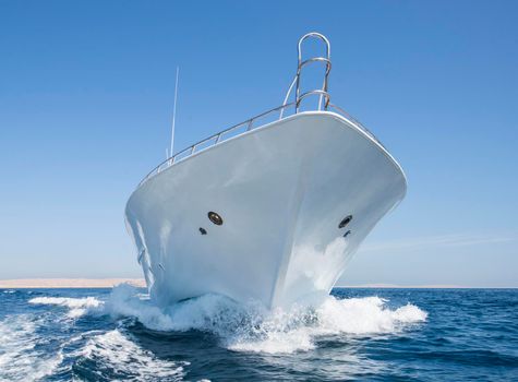Luxury private motor yacht sailing under way on tropical sea with bow wave